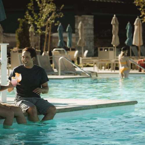 A couple enjoys cocktails by the pool at The Club at ArrowCreek