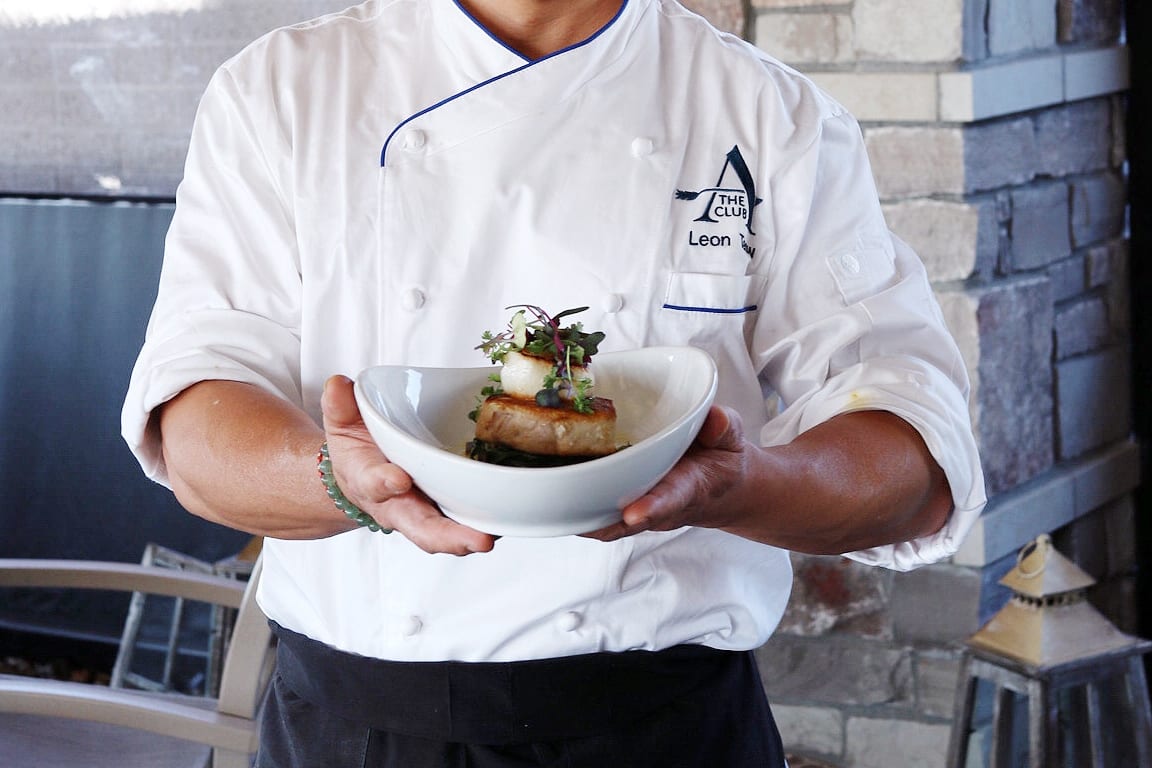 Executive Chef at The Club at ArrowCreek, Leon holding a delicious sea bass and scallop dish