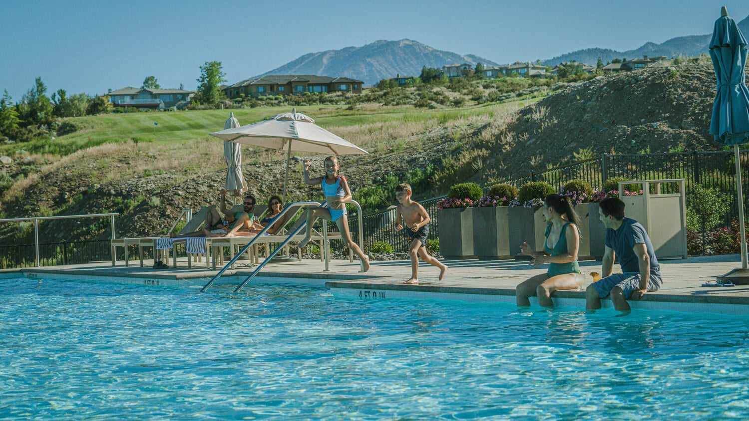 Two kids jump into the pool at The Club at ArrowCreek